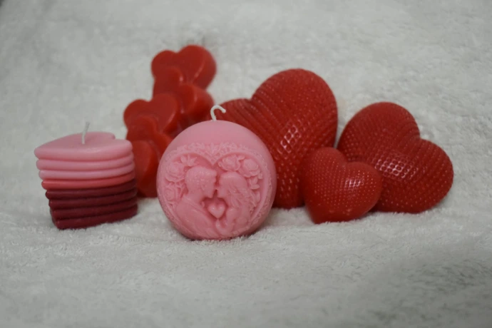 Several heart-shaped candles in red and pink.